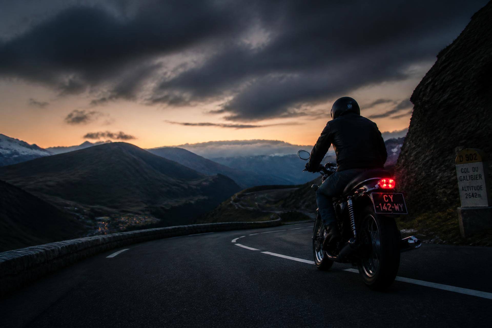 Motard sur une route de montagne en France au coucher du soleil
